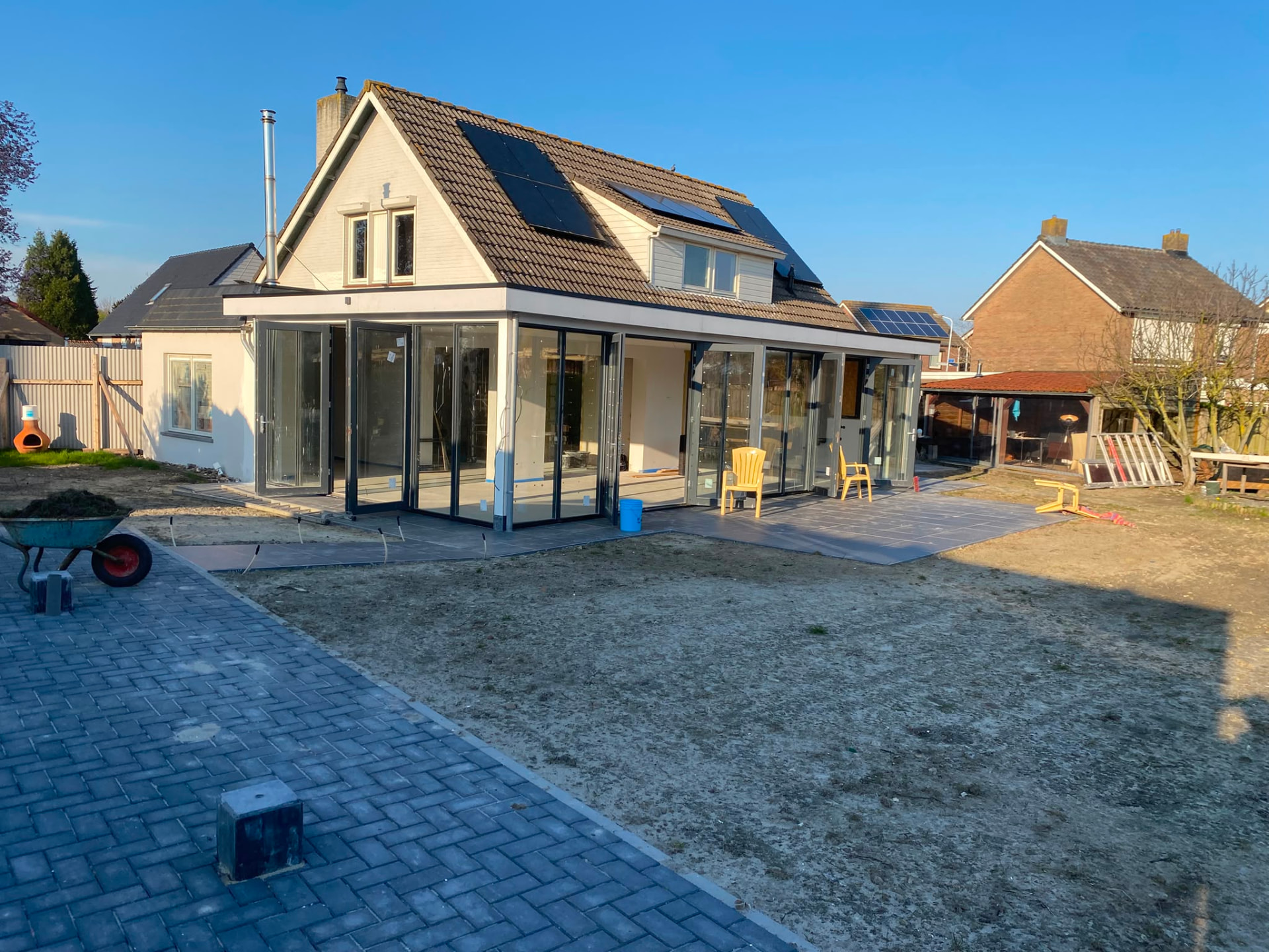House extension with large glass sliding doors and paved terrace by NIVA BUILDING